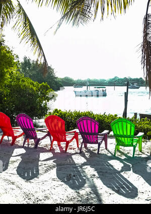 Chaises en plastique translucide coloré relaxation inviter et créer des ombres du soleil brillant sur un front de mer le long de la Gulf Intracoastal Waterway dans le comté de Sarasota, Floride, USA. Banque D'Images