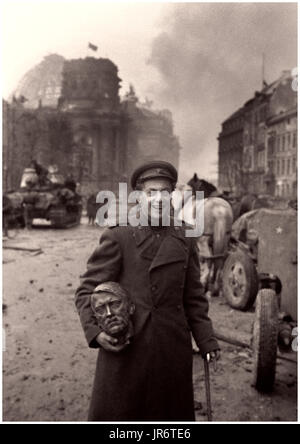 CHANCELLERIE DU REICH REICHSTAG Seconde Guerre mondiale DÉFAITE NAZIE SOLDAT RUSSE HITLER BUSTE BERLIN 1945 OCCUPATION RUSSE heureux soldat russe soviétique portant un buste de 'Fuhrer' Adolf Hitler récupéré des ruines du bâtiment de la chancellerie allemande du Reich Berlin en arrière-plan, qui est tombé à la force militaire soviétique écrasante, mai 2nd 1945 Banque D'Images