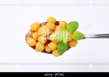 Cuillère à soupe de pois chiches cuits sur fond de bois blanc Banque D'Images