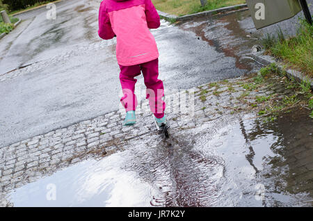 Stockholm, Suède. 4e août, 2017. Jour de pluie à Stockholm après plusieurs jours avec des chaudes journées d'été sans pluie. Fille en vêtements de pluie colorées et des bottes en caoutchouc rides son kick-bike dans les rues des pluies. Credit : Jari Juntunen/Alamy Live News Banque D'Images