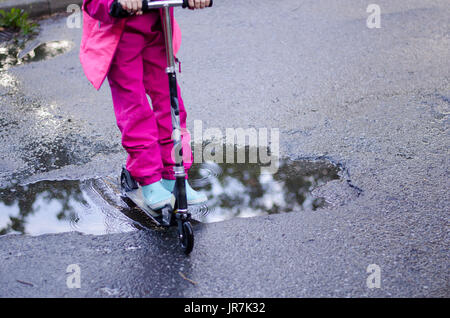 Stockholm, Suède. 4e août, 2017. Jour de pluie à Stockholm après plusieurs jours avec des chaudes journées d'été sans pluie. Fille en vêtements de pluie colorées et des bottes en caoutchouc rides son kick-bike dans les rues des pluies. Credit : Jari Juntunen/Alamy Live News Banque D'Images