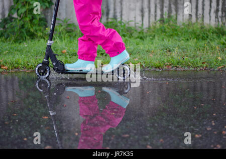 Stockholm, Suède. 4e août, 2017. Jour de pluie à Stockholm après plusieurs jours avec des chaudes journées d'été sans pluie. Fille en vêtements de pluie colorées et des bottes en caoutchouc rides son kick-bike dans les rues des pluies. Credit : Jari Juntunen/Alamy Live News Banque D'Images