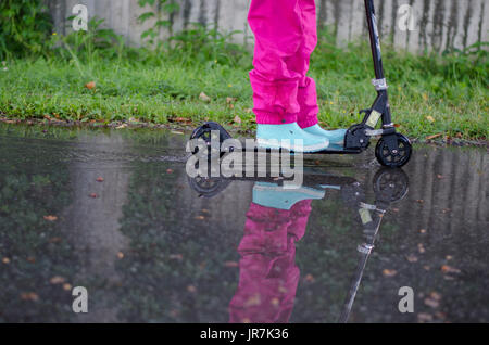 Stockholm, Suède. 4e août, 2017. Jour de pluie à Stockholm après plusieurs jours avec des chaudes journées d'été sans pluie. Fille en vêtements de pluie colorées et des bottes en caoutchouc rides son kick-bike dans les rues des pluies. Credit : Jari Juntunen/Alamy Live News Banque D'Images