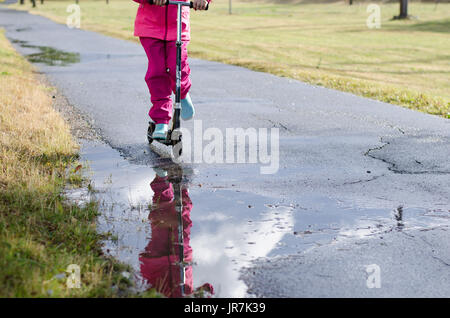 Stockholm, Suède. 4e août, 2017. Jour de pluie à Stockholm après plusieurs jours avec des chaudes journées d'été sans pluie. Fille en vêtements de pluie colorées et des bottes en caoutchouc rides son kick-bike dans les rues des pluies. Credit : Jari Juntunen/Alamy Live News Banque D'Images