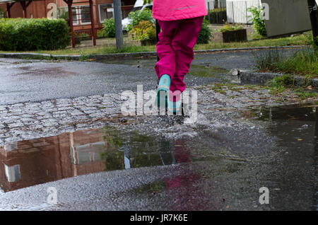 Stockholm, Suède. 4e août, 2017. Jour de pluie à Stockholm après plusieurs jours avec des chaudes journées d'été sans pluie. Fille en vêtements de pluie colorées et des bottes en caoutchouc rides son kick-bike dans les rues des pluies. Credit : Jari Juntunen/Alamy Live News Banque D'Images