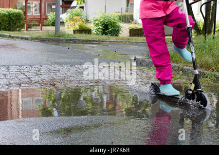 Stockholm, Suède. 4e août, 2017. Jour de pluie à Stockholm après plusieurs jours avec des chaudes journées d'été sans pluie. Fille en vêtements de pluie colorées et des bottes en caoutchouc rides son kick-bike dans les rues des pluies. Credit : Jari Juntunen/Alamy Live News Banque D'Images