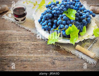 Le vin rouge et les raisins. Vin et raisin dans réglage vintage avec des bouchons sur table en bois Banque D'Images