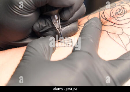 Close up d'un tatoueur de placer un tatouage à l'aide de son équipement de tatouage Banque D'Images