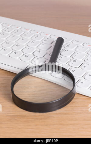 Loupe noir sur blanc pose sur le clavier de l'ordinateur de bureau, close-up high angle droit de recherche sur internet ou les options d'accessibilité concept Banque D'Images