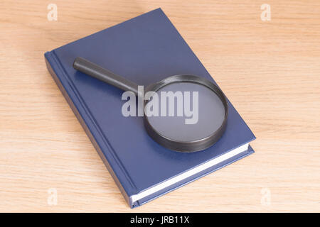 Loupe couché sur un livre bleu d'une mauvaise vision conceptuelle ou de recherche et d'analyse Banque D'Images
