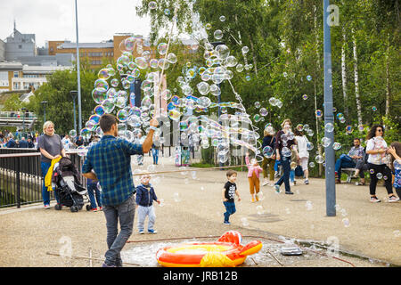 Artiste de rue aux enfants conseils sollicitation en soufflant de grandes bulles colorées, Bankside, remblai, South Bank, Londres SE1, UK Banque D'Images