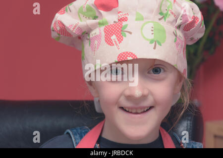 Petite fille baking cookies dans un joli tablier rose et chefs hat Banque D'Images