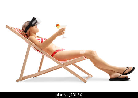 Jeune femme avec un cocktail dans une chaise longue à l'aide d'un casque VR isolé sur fond blanc Banque D'Images