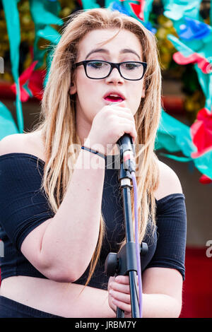 Young Caucasian woman with glasses article sur scène en chantant. Dannli Jayne, singer song writer fonctionne à plein air festival de Ramsgate eh stade. Banque D'Images