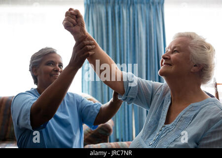 Nurse helping woman flexing muscles au nursing home Banque D'Images