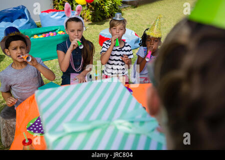 Parti de soufflage enfants horn lors anniversaire dans la cour Banque D'Images