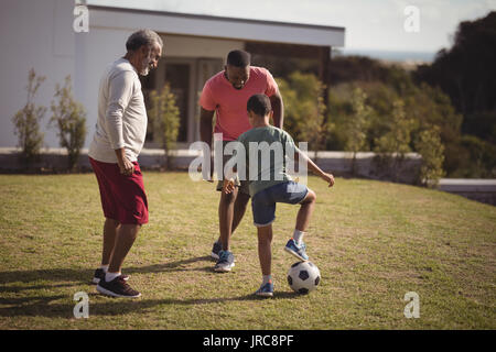 Garçon jouant au football avec son père et son petit-fils dans le jardin Banque D'Images