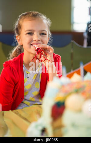 Cute girl blowing party horn lors d'anniversaire à la maison Banque D'Images