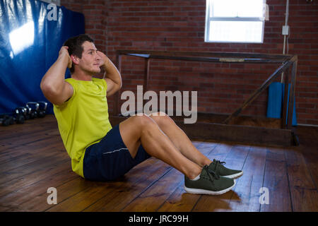 Homme déterminé effectuant craquements in fitness studio Banque D'Images