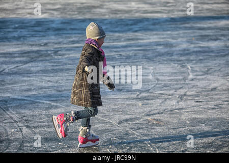 Petite fille apprendre patinoire sur glace naturelle Banque D'Images