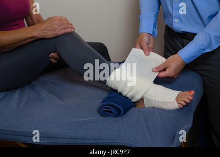 Physiothérapeute en mettant sur pieds blessés bandage de patient dans un centre Banque D'Images