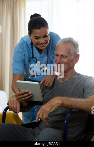 Man showing digital tablet à femme médecin en maison de retraite Banque D'Images