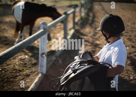 Boy holding selle de cheval sur une journée ensoleillée Banque D'Images