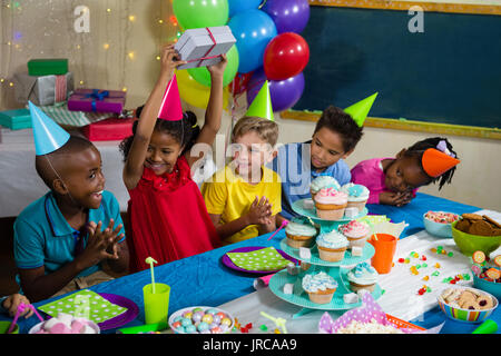 Joyeux des enfants assis à table au cours d'anniversaire Banque D'Images