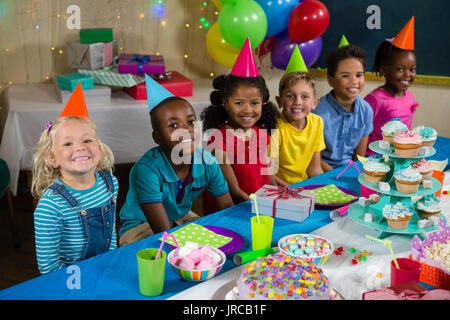 Portrait des enfants assis à table au cours d'anniversaire Banque D'Images