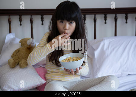 Portrait of Girl eating breakfast sur le lit chez lui Banque D'Images