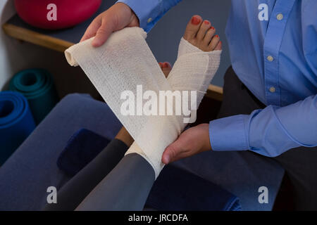 Physiothérapeute en mettant sur pieds blessés bandage de patient dans un centre Banque D'Images