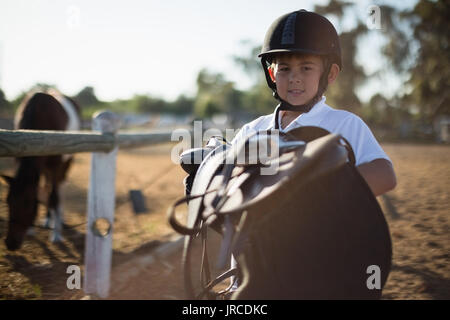 Boy holding selle de cheval sur une journée ensoleillée Banque D'Images