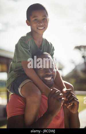 Portrait of happy father carrying son on shoulders Banque D'Images