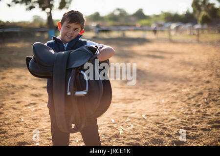 Boy holding selle de cheval sur une journée ensoleillée Banque D'Images