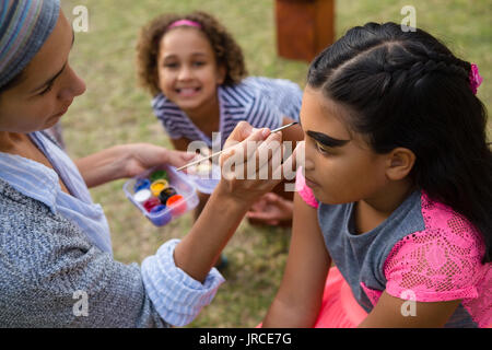 Femme faisant face paint à la fille au cours d'anniversaire Banque D'Images