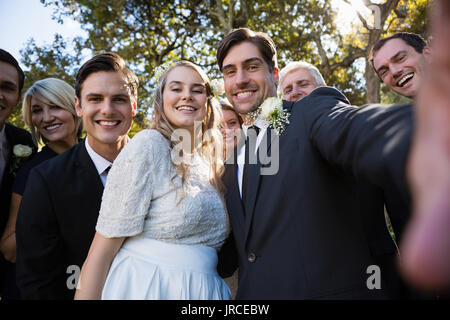 Heureux couple posant avec les clients au cours de mariage en park Banque D'Images