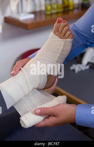 Physiothérapeute en mettant sur pieds blessés bandage de patient dans un centre Banque D'Images