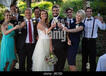 Portrait des nouveaux mariés et invités holding glasses of champagne Banque D'Images