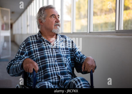 Happy man looking through window, assis sur fauteuil roulant en maison de soins infirmiers Banque D'Images