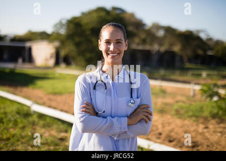 Portrait of smiling female vet with arms crossed standing à barn Banque D'Images