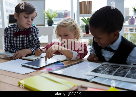 Businesswoman expliquant aux collègues masculins sur tablet in creative office Banque D'Images