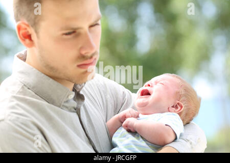 Bébé qui pleure et s'ennuient père outdoors Banque D'Images
