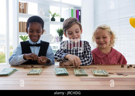 Smiling business people counting money while standing at table in creative office Banque D'Images