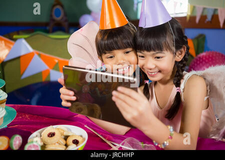 Les enfants à l'aide de tablette numérique au cours d'anniversaire à la maison Banque D'Images