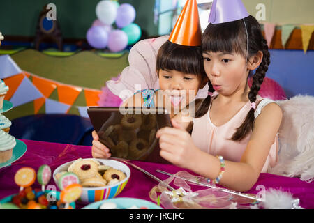 Les enfants à l'aide de tablette numérique au cours d'anniversaire à la maison Banque D'Images