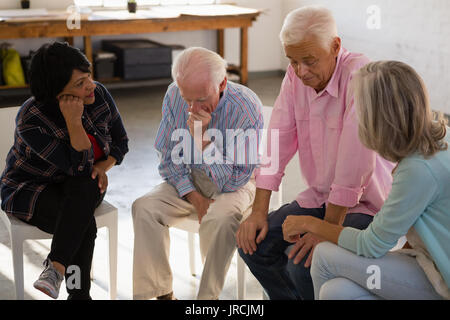 Les femmes d'amis inquiets consolante amis masculins tout en restant assis dans la classe d'art Banque D'Images