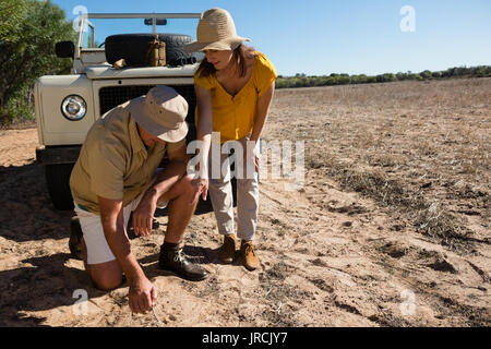 Homme avec femme de creuser le sol par véhicule hors route sur terrain Banque D'Images