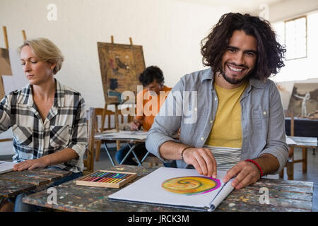 Portrait of smiling man dimensions alors qu'il était assis avec des amis dans la classe d'art Banque D'Images