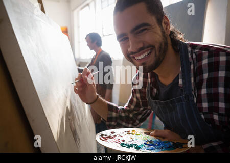 Close up portrait of smiling man peinture sur toile d'artistes dans la classe d'art Banque D'Images