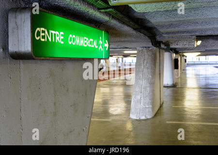 Les panneaux lumineux indiquant la direction du centre commercial dans un vieux parking souterrain décrépi. Banque D'Images